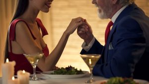 Dating with an Age Gap - Senior gentleman holding hand of tender young woman, romantic date together